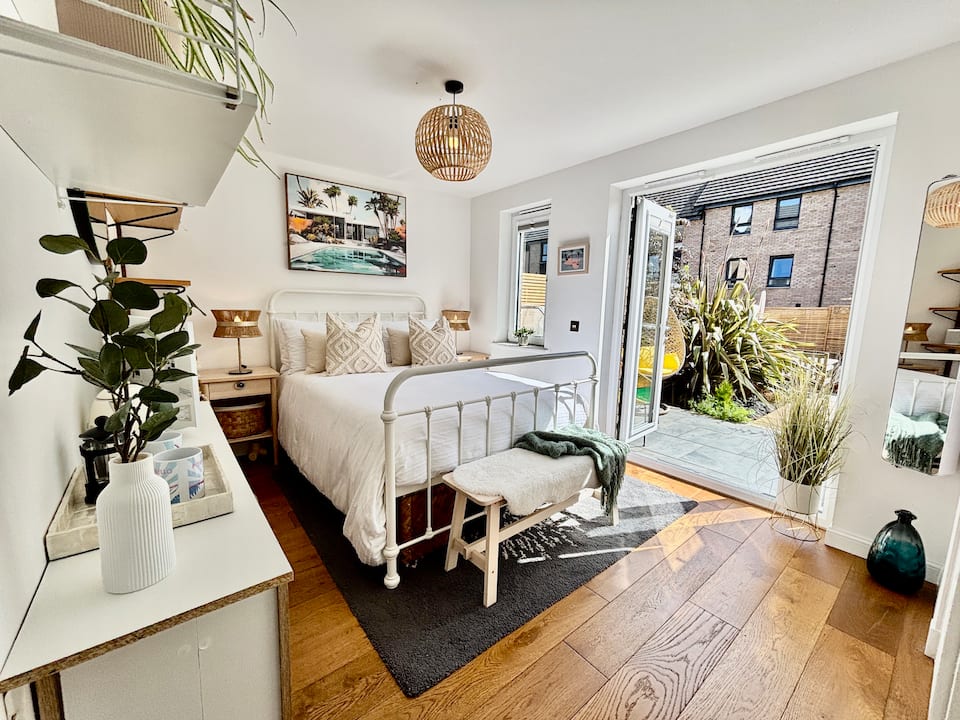 Heavenly Pad Garden Suite, with a white bed and French doors opening onto the garden patio.